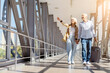 © Anastasiya - Happy senior couple walking at airport corridor with luggage, pointing aside