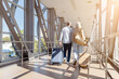 © Anastasiya - Senior couple walking away at airport corridor pulling suitcases, rear view