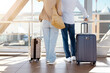 © Anastasiya - Senior couple standing with luggage at airport window, back view