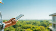 © Nattapol - Professional engineer holding tablet computer on balcony for building inspection. view shows green forest and modern home exterior
