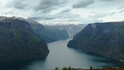 Wall Mural - Timelapse shot of a fjord near Aurland in Norway. Clouds are moving quickly across the landscape. The shadows of the clouds can be seen on the steep mountains.