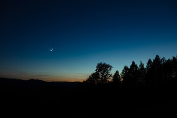 Wall Mural - Crescent young Moon with stars, planets and countryside silhouettes.