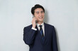 © Yamatatsu - 白背景で通話をするスーツの日本人男性