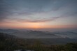 © VirtualVista - The early morning light bathes the hills and fog-covered valleys in gentle shades of coral and peach, creating a peaceful and calm atmosphere.