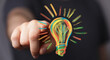 © vegefox.com - Creative idea concept.  Hand points to a colorful sketched lightbulb symbolizing innovation and inspiration.
