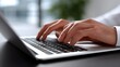 © pkproject - Close-up view of a person's hands typing on a laptop keyboard in a modern, minimalist office environment.