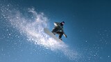 a teenager snowboarding against a clear blue sky. The image, taken from a low angle, highlights the snowboarder in the center of the composition