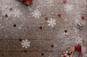 Wall Mural - Romantic holiday card featuring a teddy bear, hearts, and snowflakes on a wooden surface, festive winter decoration with white snow flakes, overhead shot