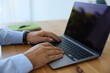 © New Africa - Man working on laptop at wooden table indoors, closeup