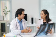 © amnaj - Asian doctors collaborating and discussing an X ray film, analyzing medical results for patient healthcare and treatment plan