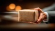 © Sawali - A person's hand holds a brown package, suggesting rapid delivery or a sense of urgency in the scene.