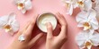© Karyn - The Moisturizer Jar and Hands Applying Cream Surrounded by White Orchids on Pink