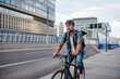 © Halfpoint - Urban commuter cycling on street carrying backpack.
