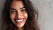 © Johannes - close up face of young woman with beautiful smile isolated on grey wall with copy space successful multiethnic girl latin woman looking at camera against gray wall with a big whitening teeth smile no