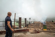 © Lupe Rodriguez/Stocksy - worker sweeping the top of a furnace in a charcoal factory
