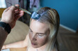 © Dmitri - Process of coloring hair at home, applying dye with a brush to a woman's blonde roots for a color refresh.