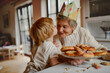 © Halfpoint - Grandmother in paper crown receiving kiss from grandchild.