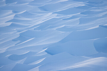 Wall Mural - Snow texture. Wind sculpted patterns on snow surface. Wind in the tundra and in the mountains on the surface of the snow sculpts patterns and ridges (sastrugi). Arctic, Polar region. Winter background
