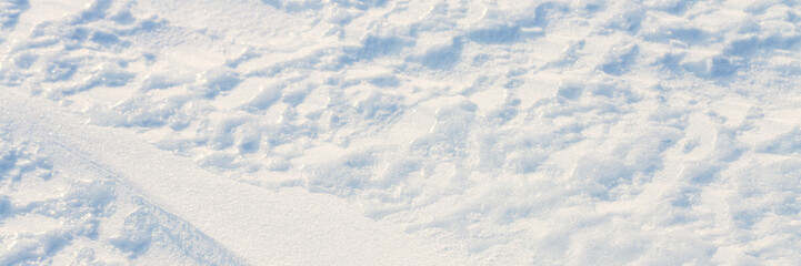 Wall Mural - Beautiful winter background with snowy ground. Natural snow texture. Wind sculpted patterns on snow surface. Wide panoramic texture for background and design. Closeup top view with copy space.