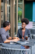 © Jovo Jovanovic/Stocksy - Two people talking at an outdoor cafe table.