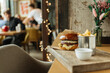 © Pietro Karras/Stocksy - Cheeseburger and fries served in cozy restaurant