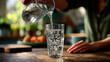 © HA - Pouring refreshing water from a glass pitcher into a glass on a wooden table top