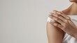 © baoxiangbin - A Woman’s Hand Applies Lotion to Her Shoulder Against a White Background—Showing Smooth Moisturizer Spread, Gentle Massage, and Focus on Shoulder Skin Care in a Clean, Minimalist Setting