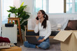 © itchaznong - Remote Work: Young Woman on Phone While Setting Up New Home Office