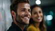 © Bussakon - A man and a woman smiling collaboratively in a modern office setting with a blurred background