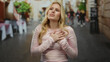 © Krakenimages.com - Young blonde woman experiencing chest pain on a city street, displaying concern and discomfort amid urban surroundings, evoking themes of health or anxiety outdoors.