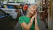 © Krakenimages.com - Senior woman with grey hair and tattoos stands peacefully with eyes closed on a busy city street, surrounded by cars and urban scenery, evoking a sense of calm and mindfulness.
