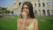 © Krakenimages.com - Girl bites nails in front of historic roman coliseum building outdoors on sunny day amid scattered tourists; nervousness.
