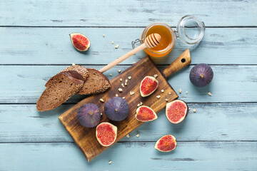 Wall Mural - Composition with cutting board, fresh ripe figs, toasts and jar of honey on blue wooden background