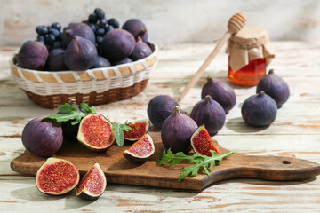 Wall Mural - Cutting board with fresh ripe figs and arugula on white wooden background
