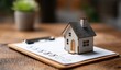© AndiAzis - Miniature House Model on a Real Estate Document with Pen and Clipboard