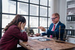 © Tj - Female client sitting at a desk, covering her face and looking stressed while a male lawyer, gesturing with his hand and holding a gavel, is scolding her in an emotional legal consultation
