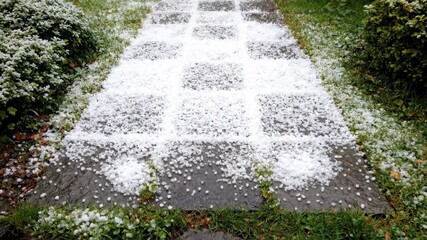 Wall Mural - Dynamic time lapse showing a pathway completely covered by hail, then gradually clearing as it melts hail, clean, spring