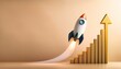 © Janet - rocket launching beside rising bar graph and arrow on beige background symbolizing business growth and success with clean copy space