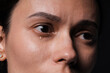 © New Africa - Sad woman crying on black background, closeup