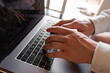 © VasylisaDvoichenkova - Close-up of a man's hands typing on a laptop keyboard. The hands are medium-toned with visible veins and well-groomed nails. The laptop is silver and modern.