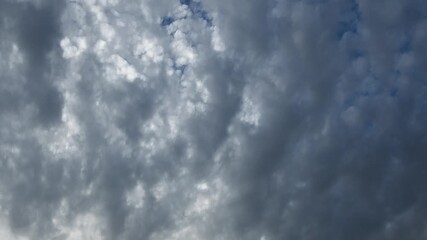 Wall Mural - Looking straight up at a sky full of light to dark gray clouds moving in a time lapse
