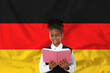 © New Africa - Little girl with book against flag of Germany. Language school