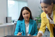 © amnaj - Asian businesswomen discussing work using a laptop in a modern office, focusing on teamwork and mentoring