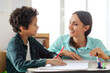 © Home-stock - Happy female teacher helping Latin boy with task in secondary school during test. Support, scholarship and educator aid