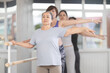 © JackF - Group of female beginners practicing second ballet position at barre in dance studio