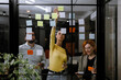 © Nikola Spasenoski - Team collaboration during brainstorming session in modern office with sticky notes on glass wall