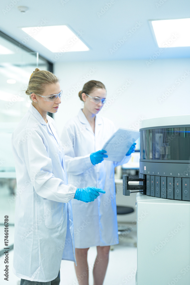 Two female laboratory scientists collaborate in a modern clinic. One ...