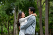 © bongkarn - Young asian couple of man and woman holding and hugging each other while standing outdoors in park.
