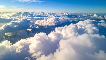 Wall Mural - High white cumulus clouds drift over the blue mountain landscape in the clear day air