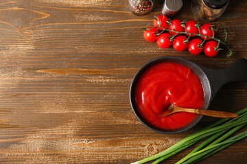 Wall Mural - Bowl of tasty tomato sauce and green onion on wooden background